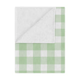 Sage Gingham minky baby blanket draped over a crib