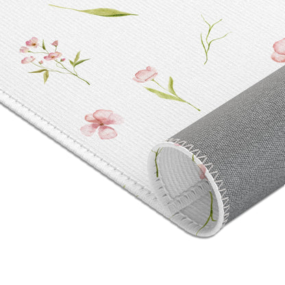 Dusty pink floral area rug beside a nursery crib