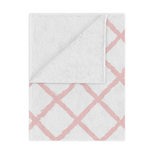 Pink trellis minky baby blanket draped over a crib