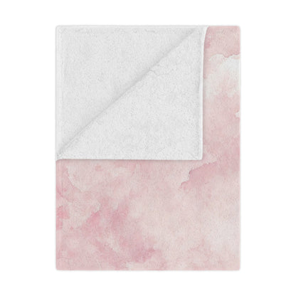 Pink watercolor clouds minky baby blanket draped over a crib