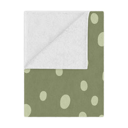 Sage Speckle minky baby blanket draped over a crib